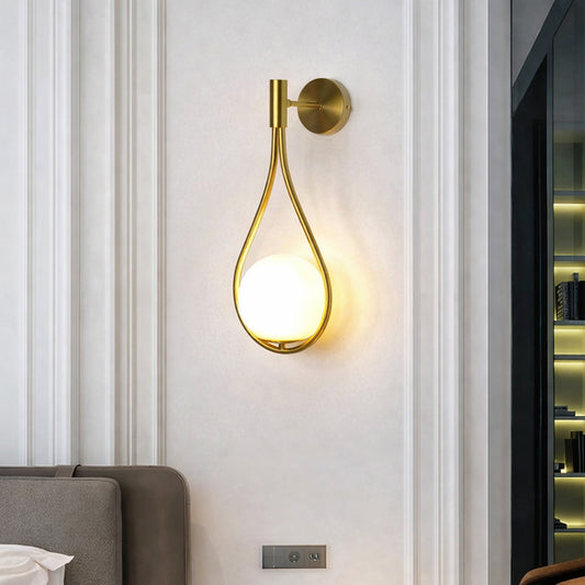 Modern gold metal wall light with white glass globe for elegant bedroom and luxury decor styling spaces.

