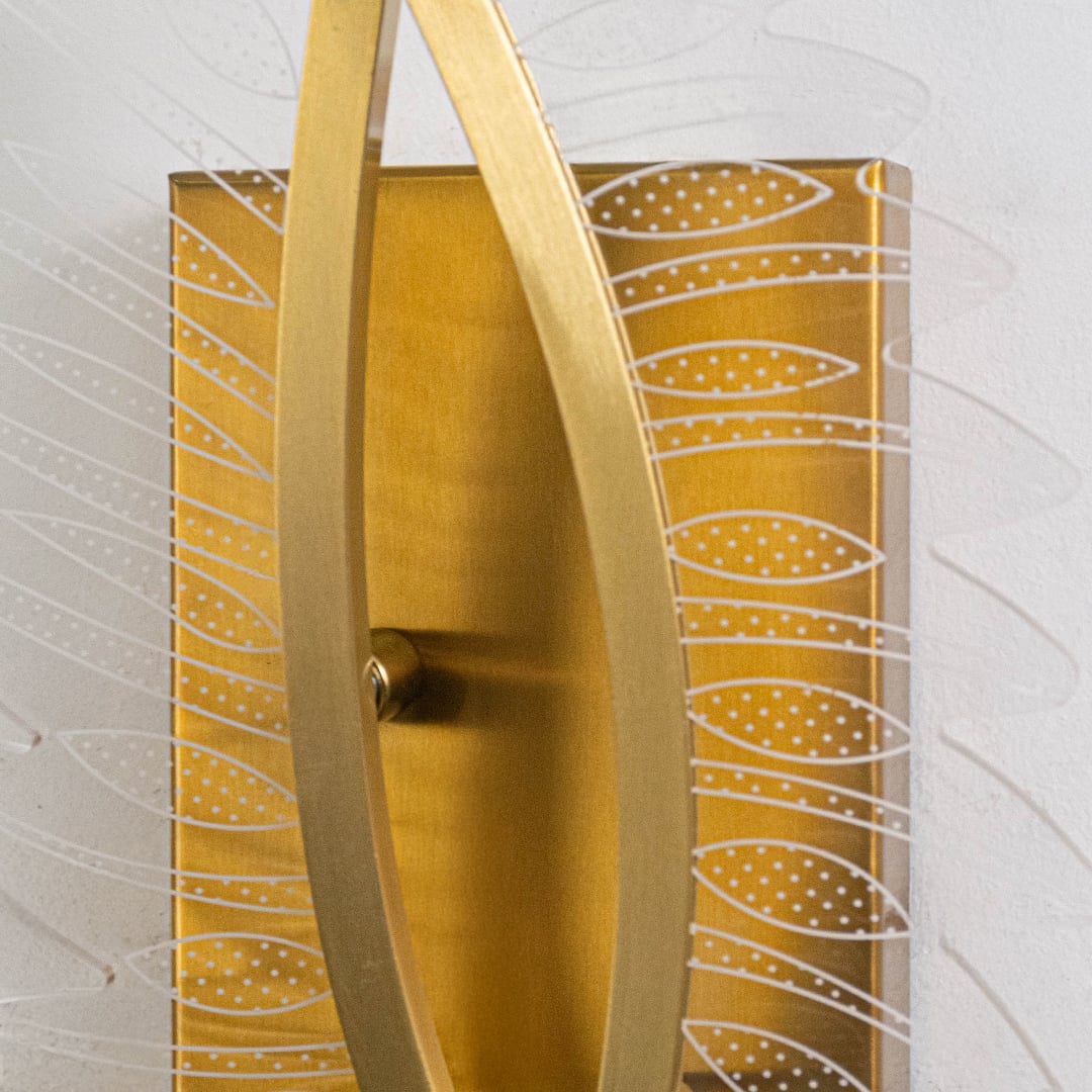 Closeup of gold wall light with sculpted acrylic panels highlighting artistic curves and premium textured finish.