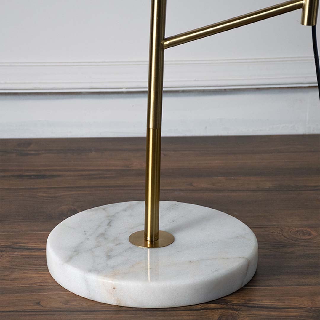 Closeup of gold metal table lamp stem fixed on round white marble base highlighting smooth finish premium material and modern craftsmanship.
