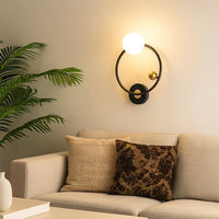 A modern metal wall light with a round glass globe mounted beside a sofa on a beige wall creating warm ambient lighting and enhancing elegant contemporary décor.