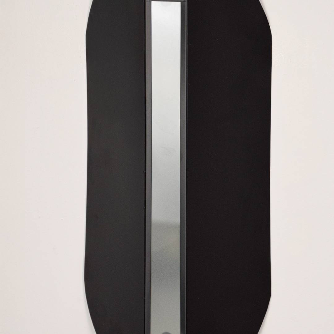 Wall light closeup highlighting smooth black metal finish with soft glowing center showcasing premium craftsmanship and architectural design.