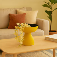 Yellow pedestal bowl with black interior styled in a modern living space adding bold artistic decor to shelves and tabletops.