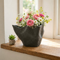 Organic black textured vase filled with colorful flowers on wooden windowsill for bright modern home floral displays.