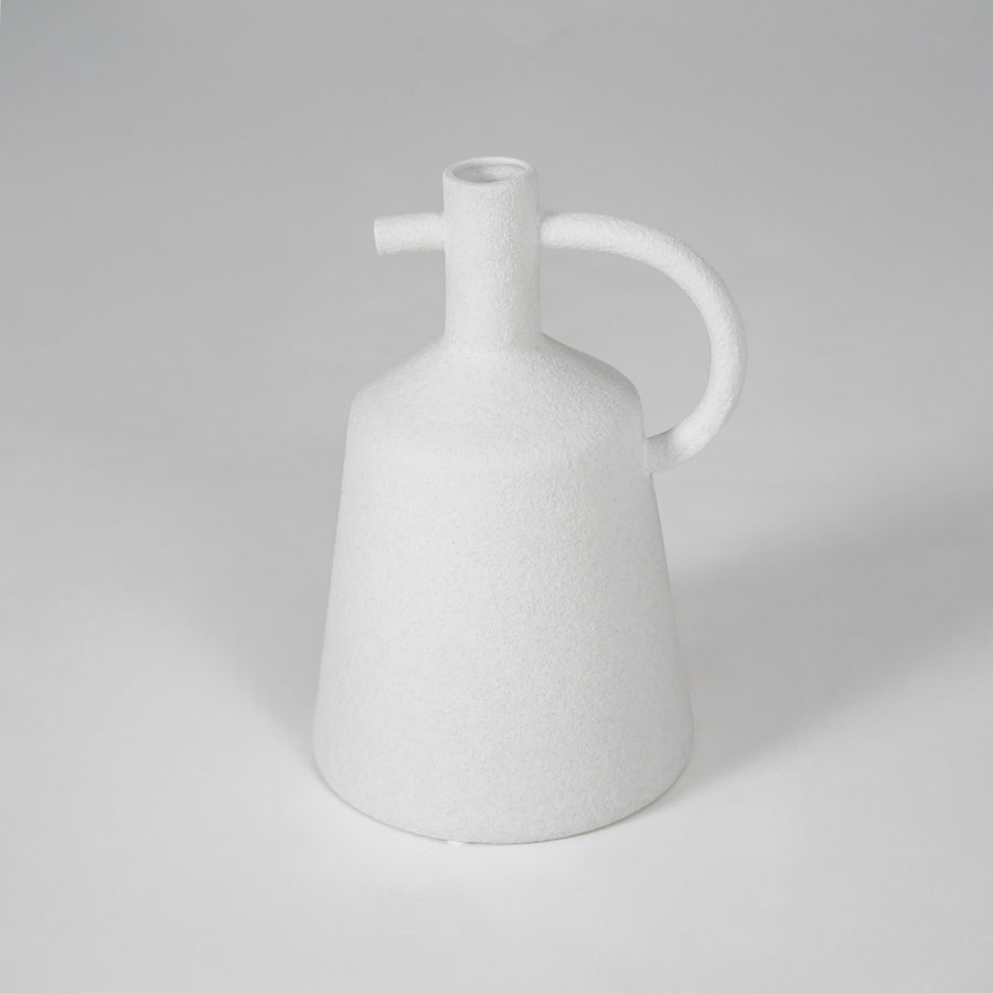 White ceramic vase with curved handle for modern shelf placement and elegant indoor decor styling accent piece.