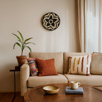 A handwoven natural and black rattan wall decor plate styled above a beige sofa with warm cushions a wooden table and soft neutral accents creating cozy modern home vibes.