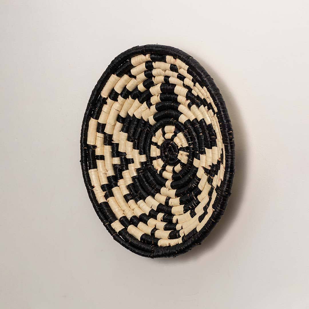 Side view of handcrafted black and cream seagrass wall basket with geometric flower pattern for bohemian home wall décor.