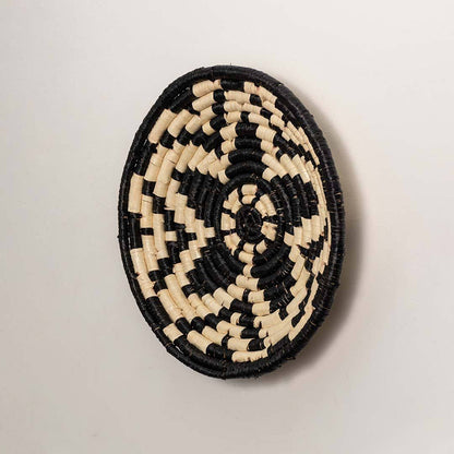 Side view of handcrafted black and cream seagrass wall basket with geometric flower pattern for bohemian home wall décor.