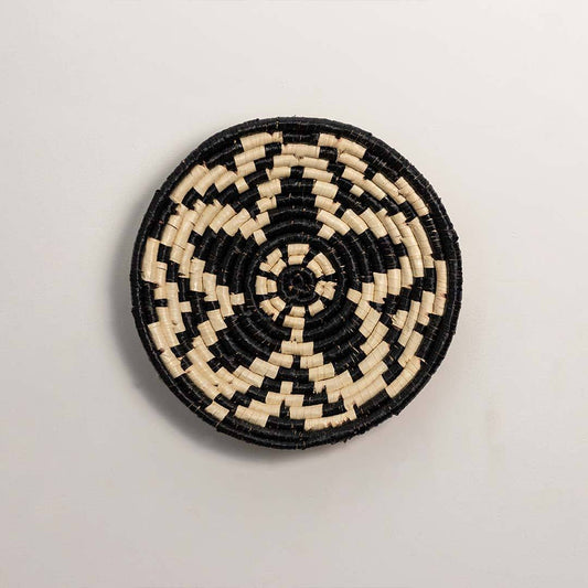 Round handcrafted black and cream seagrass wall basket with woven geometric floral star pattern on white background image.