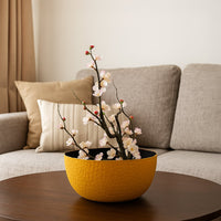 Yellow hammered metal bowl with black interior styled in a warm minimal setup adding a bright modern touch to decor.