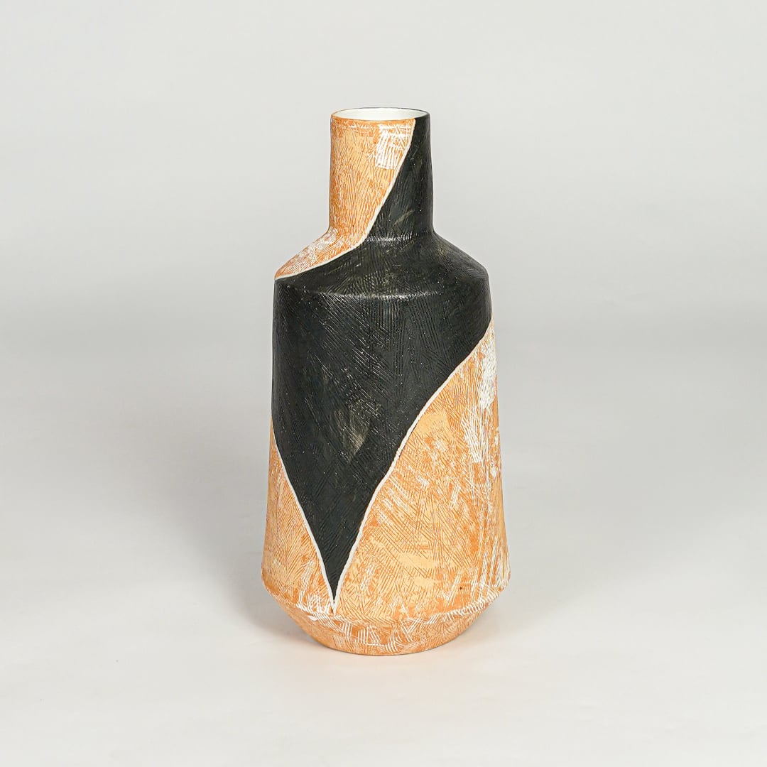 Modern orange and black ceramic statement vase with geometric sculpted body for shelf console or table styling.