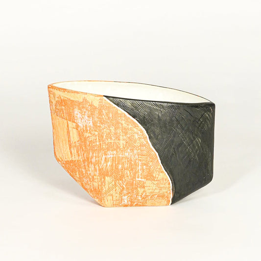 Modern orange and black ceramic statement planter with asymmetrical shape for coffee table console or shelf styling.