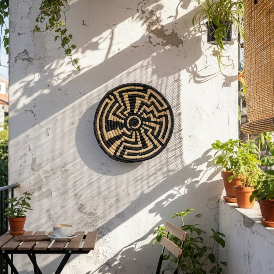 Nature inspired round wall decor mounted on balcony wall complementing plants and sunlight to create serene outdoor decor with organic visual balance.