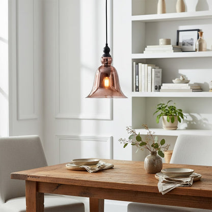 Black metal pendant light with amber glass shade illuminating dining area with vintage charm.