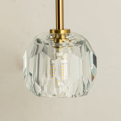 A closeup of the gold metal wall light highlighting the detailed faceted crystal shade and smooth metallic arm for a luxurious modern lighting finish.