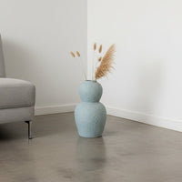 Light blue textured decorative vase arranged in a styled interior adding sculptural artistic decor to living rooms entryways and designed spaces.