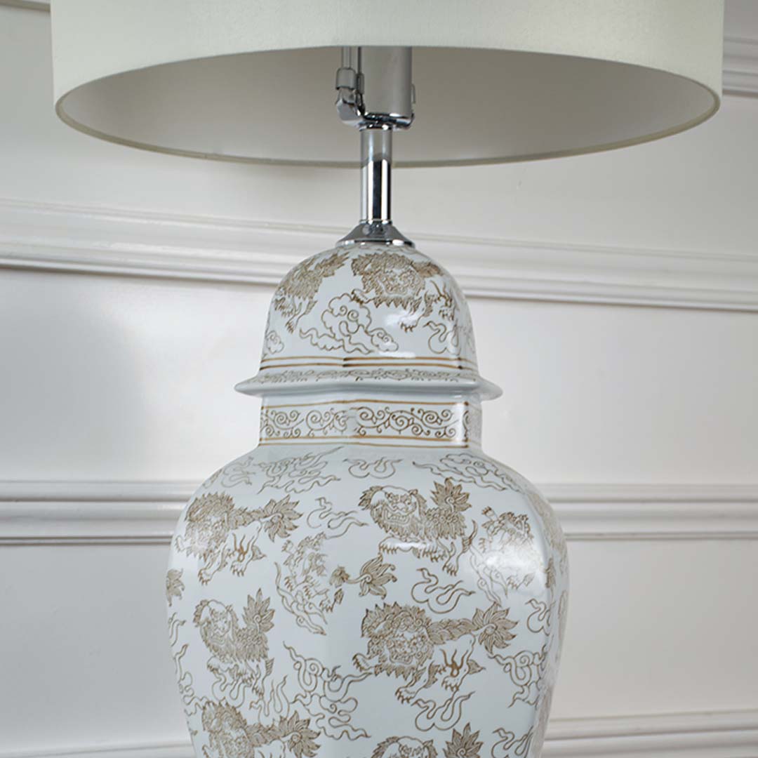 Closeup of ceramic table lamp base with golden floral design and white drum shade highlighting details and craftsmanship table lamp.