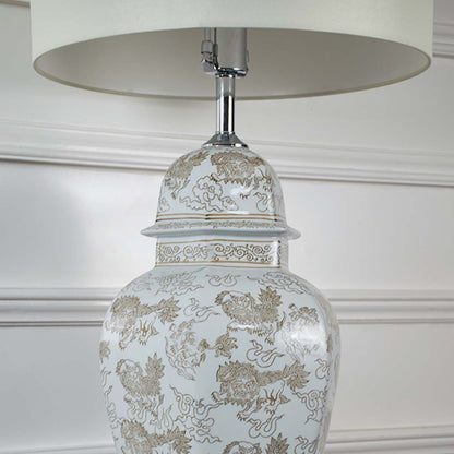 Closeup of ceramic table lamp base with golden floral design and white drum shade highlighting details and craftsmanship table lamp.