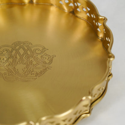 Closeup view of antique gold metal serving tray highlighting ornate engraving and handcrafted edge detailing.