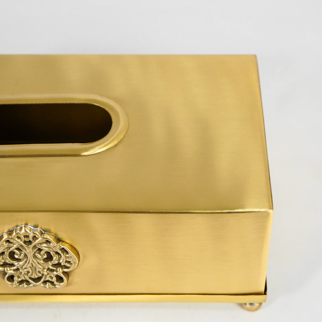 Closeup view of antique gold metal tissue box holder highlighting brushed finish and ornate floral detailing.