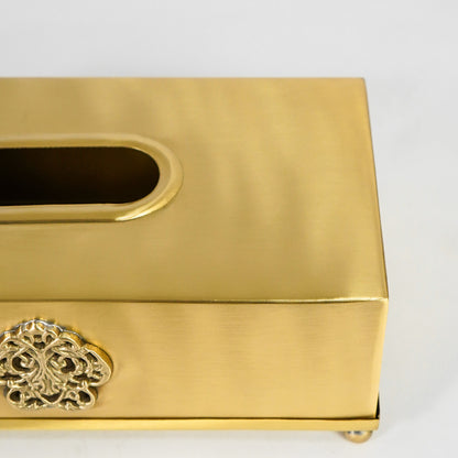 Closeup view of antique gold metal tissue box holder highlighting brushed finish and ornate floral detailing.