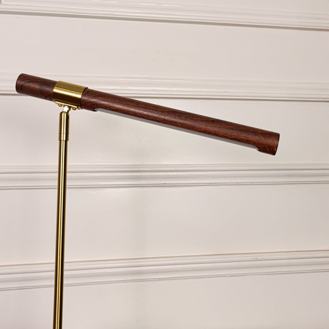 Closeup of gold metal desk lamp highlighting wooden tube light head smooth satin finish precision joints and modern design detail.