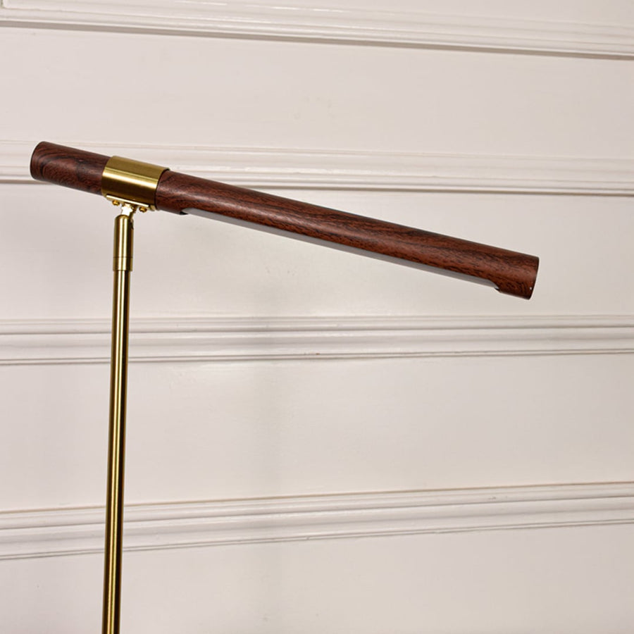 Closeup of gold metal desk lamp highlighting wooden tube light head smooth satin finish precision joints and modern design detail.