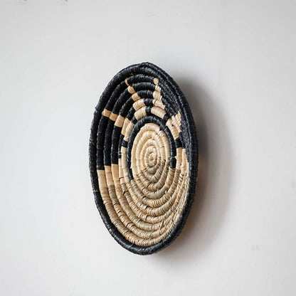 Side view of handcrafted woven wall basket showing slim profile tight coil weaving and natural straw texture suitable for wall hanging decor.
