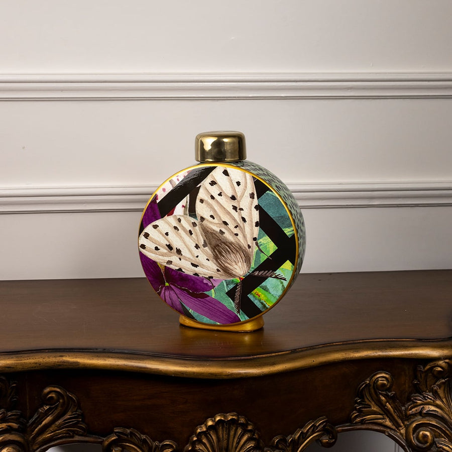 Butterfly design ceramic jar on a plain white background focusing on its round shape and striking color contrast.