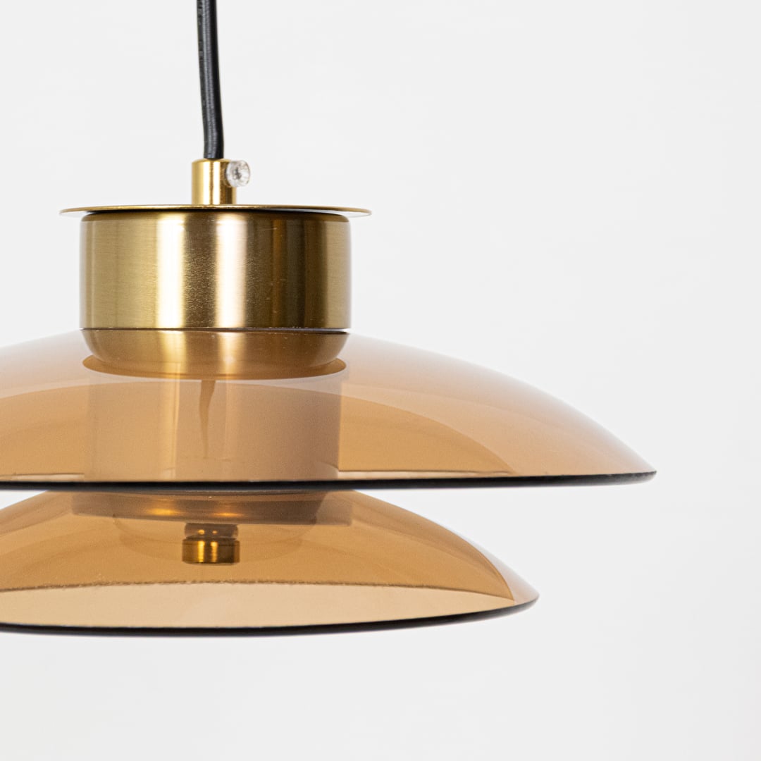 Close view of amber glass pendant light showing gold metal detailing and layered glass shade design with smooth modern craftsmanship.