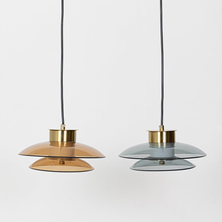 Grouped amber and smoky grey glass pendant lights with gold metal fittings shown with lights off highlighting their sculpted layered glass form.
