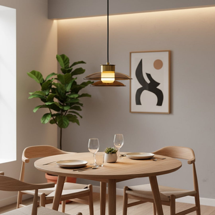 Elegant brass and amber glass pendant light glowing warmly above a modern dining table creating a cozy decor setting in a minimalist room.