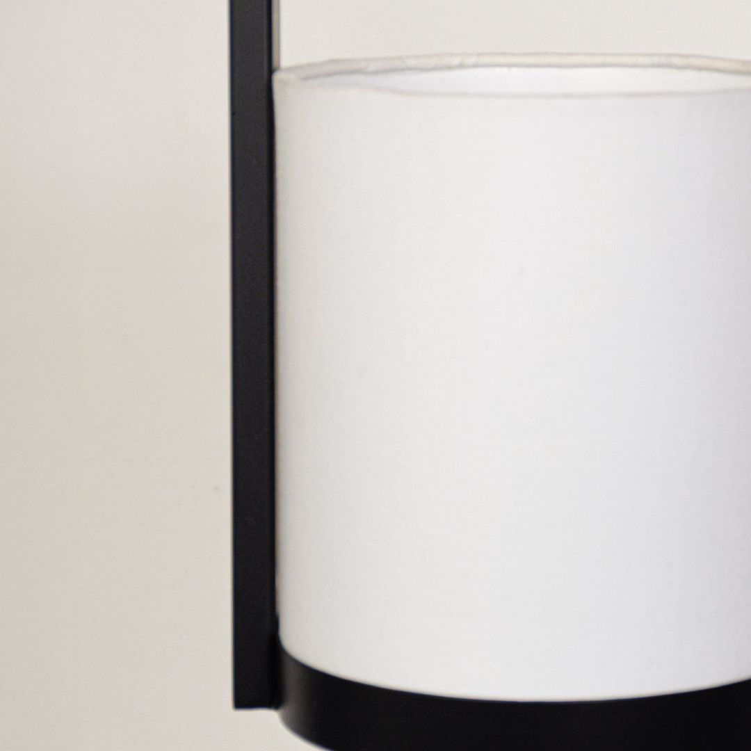 Closeup of black metal pendant light with white fabric shade for elegant modern lighting decor styling ideas.