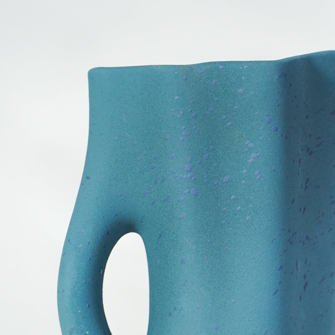 Closeup image of blue ceramic abstract vase for modern console table decor styling with matte textured finish.