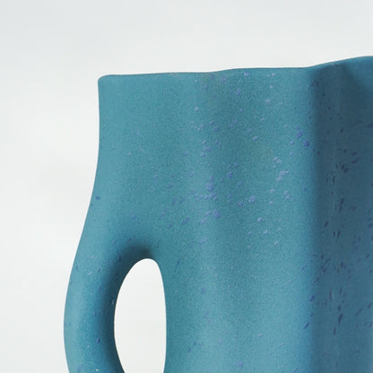 Closeup image of blue ceramic abstract vase for modern console table decor styling with matte textured finish.