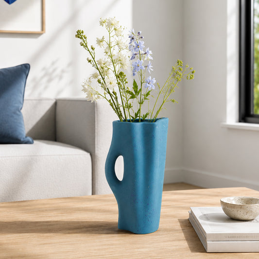 Blue ceramic flower vase with fresh blooms placed on wooden table for modern home decor styling.