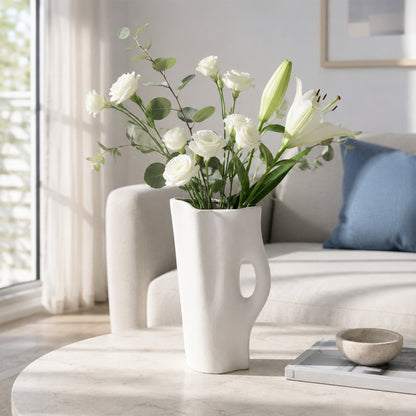 White ceramic flower vase with fresh blooms placed on marble table for elegant modern decor styling.