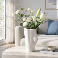 White ceramic flower vase with fresh blooms placed on marble table for elegant modern decor styling.
