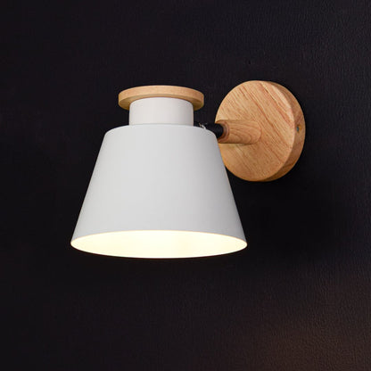 Contemporary wooden wall sconce with white conical lampshade glowing warm light on black background for bedroom hallway and modern home decor.