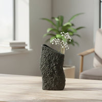 Black textured ceramic decorative vase styled with greenery on a table for modern minimalist home decor settings.