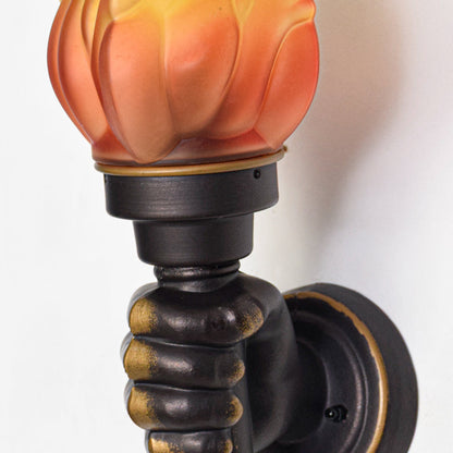 Close view of decorative wall sconce with orange flame glass shade and detailed black metal holder showcasing antique style lighting design.