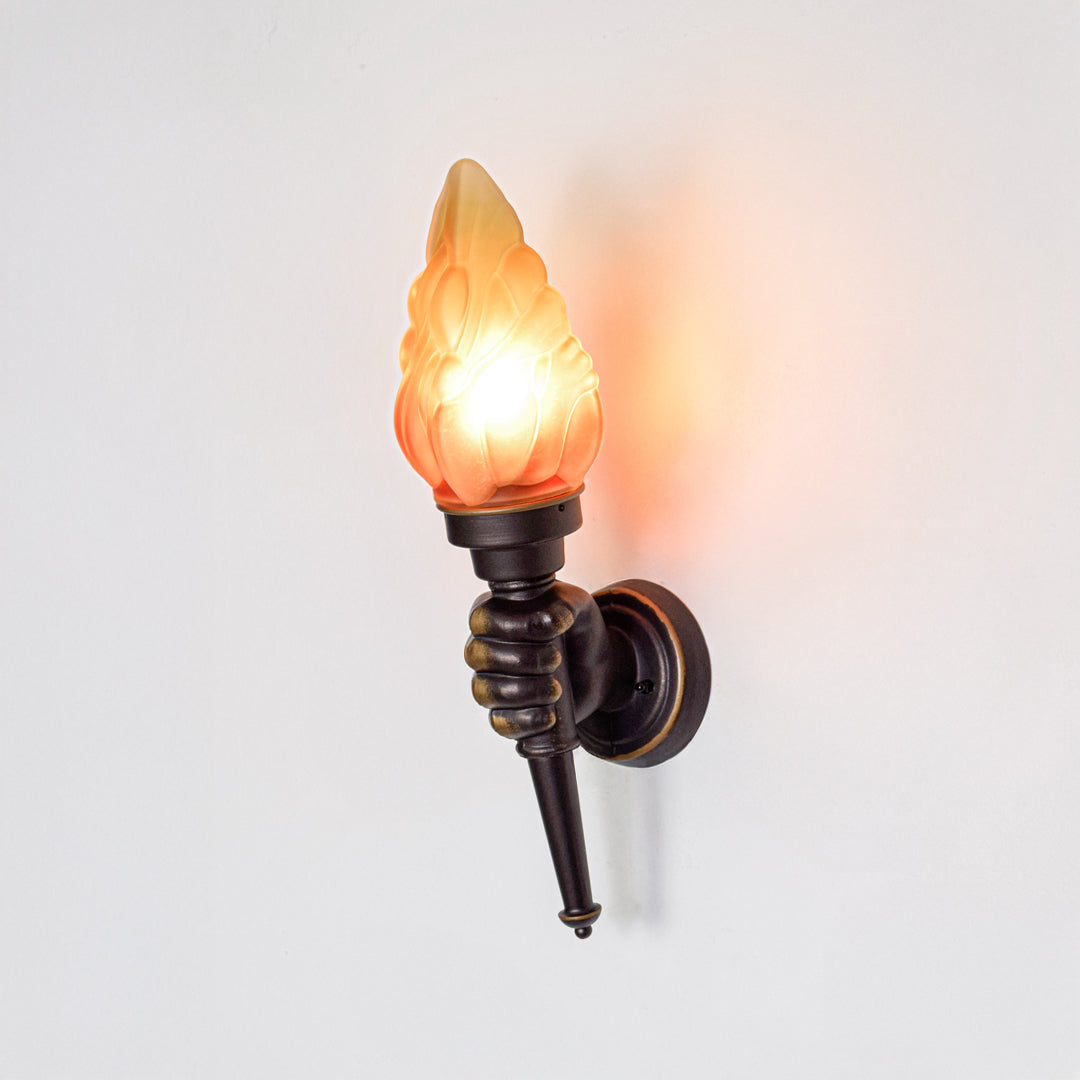 Vintage wall light with flame shaped glass shade and black metal base mounted on neutral wall background ideal for classic interior decor lighting.