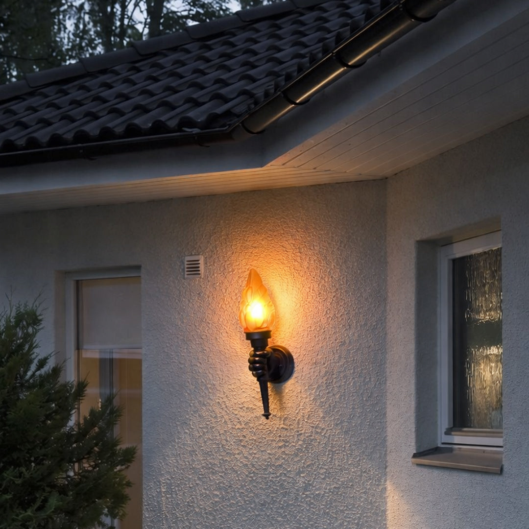 Traditional outdoor wall light with flame effect glass shade mounted on exterior wall creating warm ambient entrance lighting.