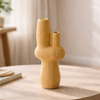 Mustard ceramic flower vase with ribbed texture placed on wooden table for modern home decor styling ideas.