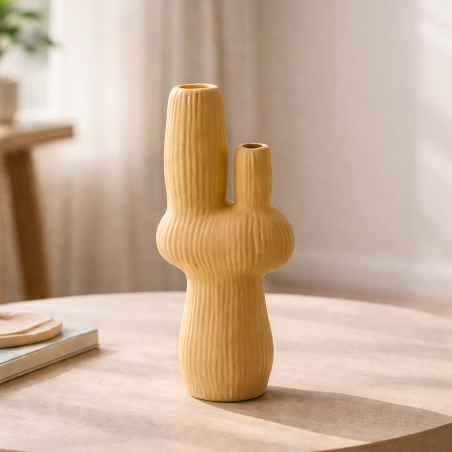 Mustard ceramic flower vase with ribbed texture placed on wooden table for modern home decor styling ideas.