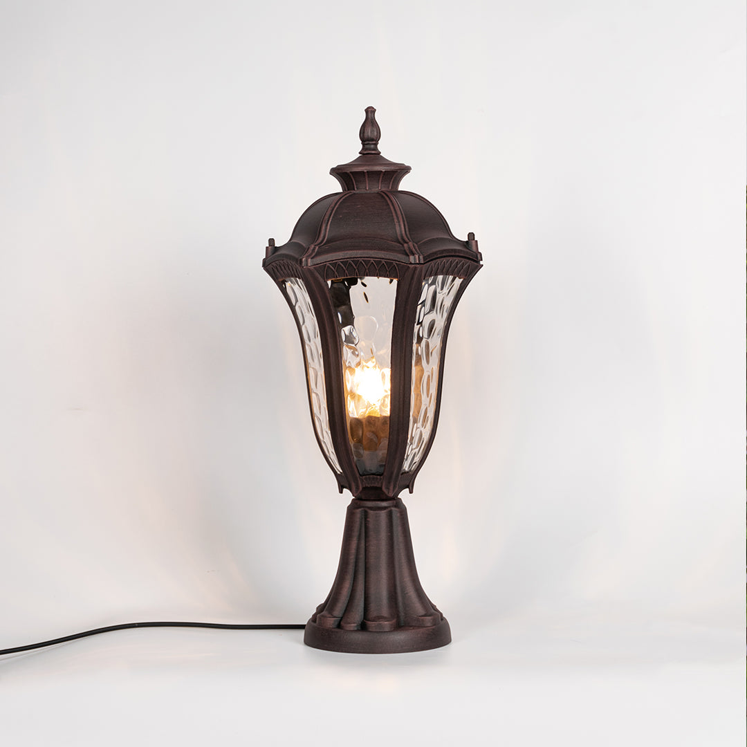 Vintage outdoor gate light with black metal frame and warm glowing glass shade for elegant decor use.