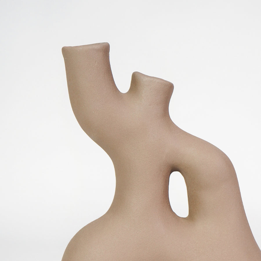 Closeup image of beige ceramic abstract vase for modern shelf placement with elegant matte artistic styling display.