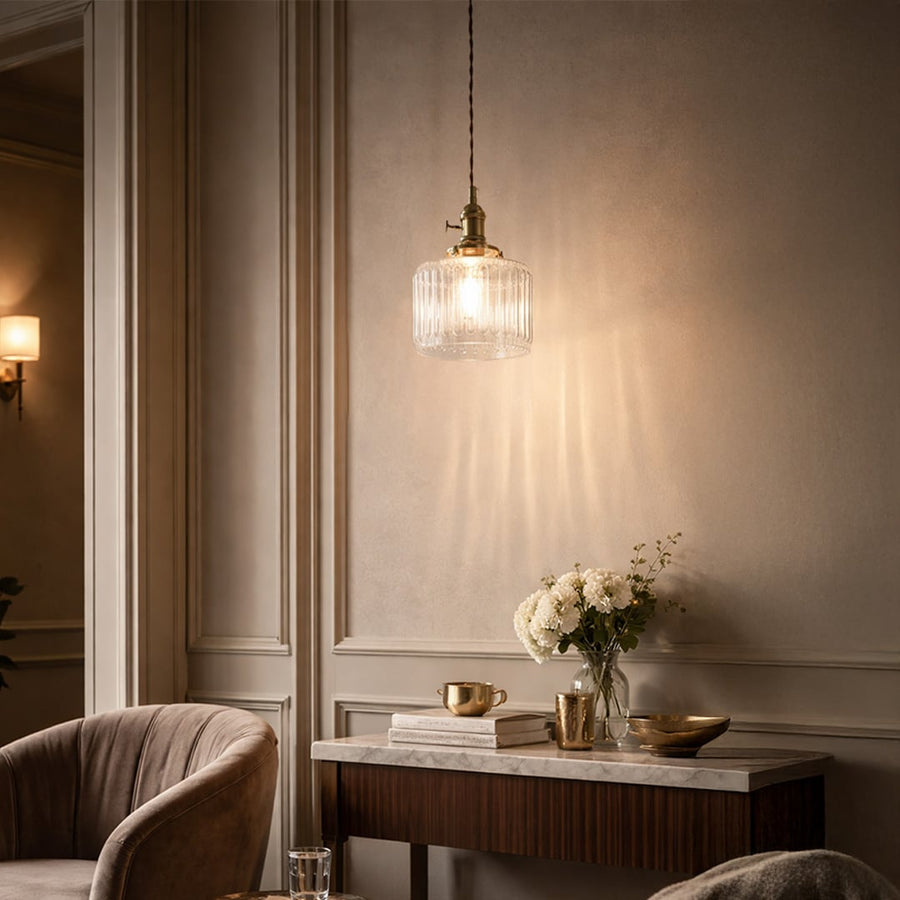 Textured clear glass and brass metal pendant light adding warm charm to cozy bedroom interiors.