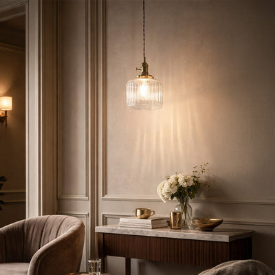 Textured clear glass and brass metal pendant light adding warm charm to cozy bedroom interiors.