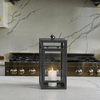 Lifestyle image of medium black metal candle lantern for rustic patio decor styling and modern outdoor home patio lighting.