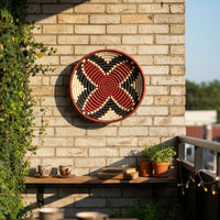 Woven round wall basket displayed on brick wall balcony adding bold texture greenery and relaxed outdoor home Decor charm.